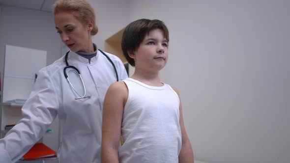 Portrait of Boy Standing in Pediatric Clinic As Doctor Measuring Body with Tape alt