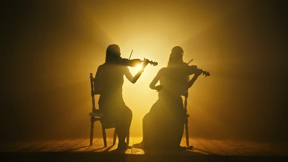 Silhouettes of Girls Violinists Professionally Playing Violins on the Large Stage of theChamber Hall alt