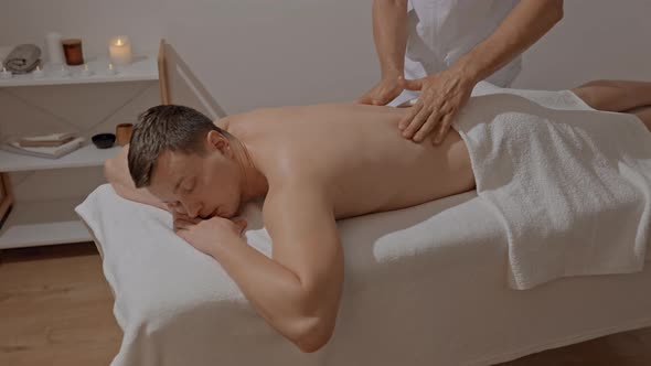 Male Hands Making Professional Back Massage in SPA Salon or Clinic