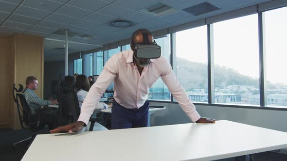 African American businessman wearing VR headset in modern office alt