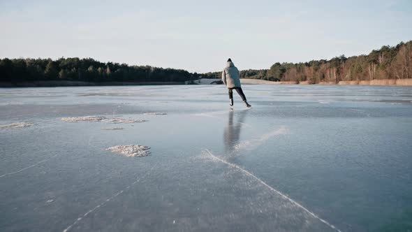 Man Practicing Ice Skating on a Clear Frozen Lake on a Sunny Winter Day