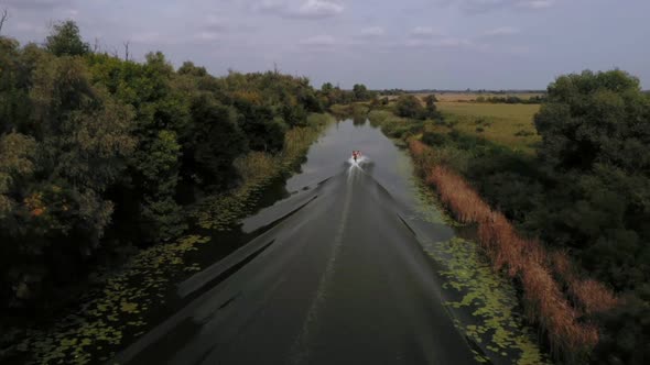 Aerial Shot Following Speed Boat in the Narrow Swamp River in the Woods Ukraine