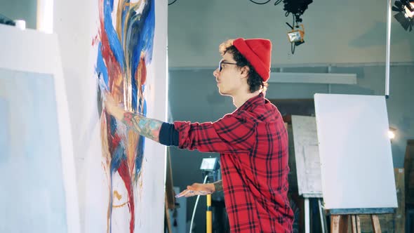 Young Man is Painting a Picture with Bare Hands alt