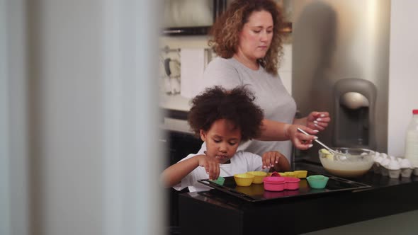 Little Black Girl Lays Out Small Cake Moulds and Eats the Rests Out of the Mould alt