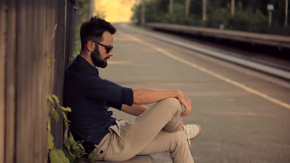 Businessman Hurries To Work And Sitting On Railway Train Station Platform. Μan Waiting Transport . alt