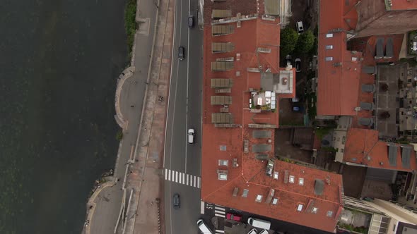Red rooftops and city traffic on small road near river Po, top down aerial view alt