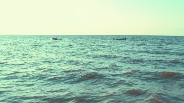 Two Boats Float in Different Directions in the Sea on the Waves