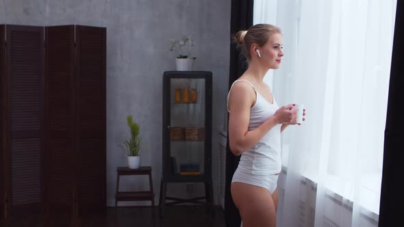 Young  girl is standing in front of the window alt