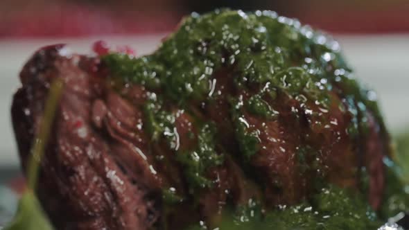 Close-up of juicy fried beef steak filet mignon on a plate with green herb sauce alt