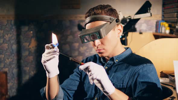 Jeweller Welds Metal Ring with a Burner. A Goldsmith in Jewelry Working with Ring. alt