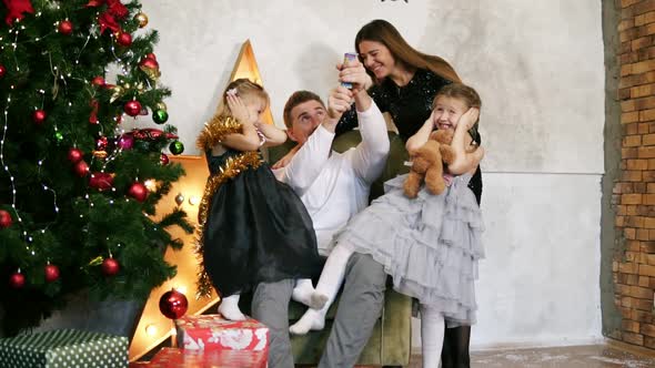 Family of Four Having Fun with Petards Sitting By the Decorated Christmas Tree alt