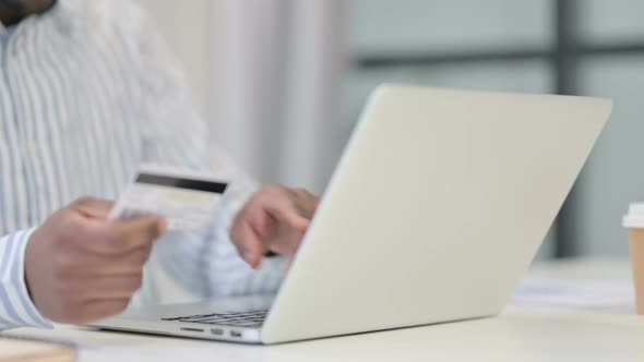 Close Up of African Man Making Online Payment on Laptop alt