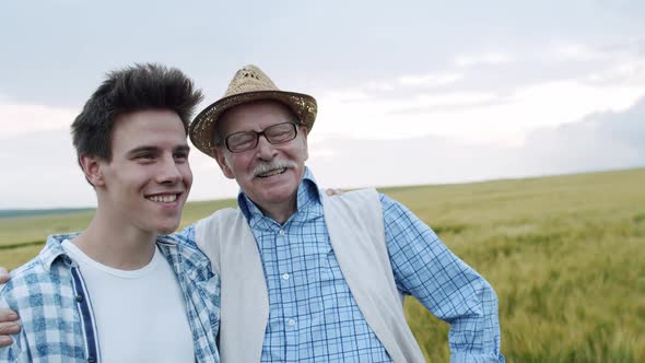 Portrait of Happy Senior Farmer with Son Standing and Smiling in Barley Field alt