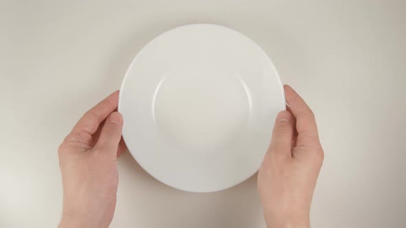 Human Hands Puts A White Dish On A White Table