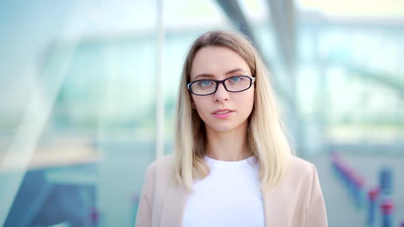 Close up portrait young blonde business woman with glasses looking at camera smiling