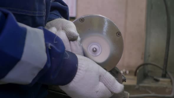 A Worker Burnishes the Finished Silver Spoon with a Machinetool alt