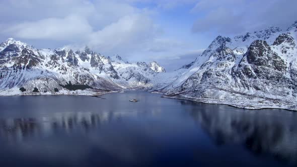 Beautiful aerial truck right shot of snow covered Austnesfjorden mountains in Lofoten Norway, with c alt
