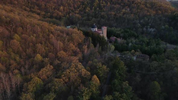 Panoramic view of church nestled into forest on a mountain in autumn. Ornate architecture