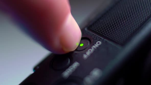 the Finger Presses the on Off Button of the Video Camera and the Green Light Turns on