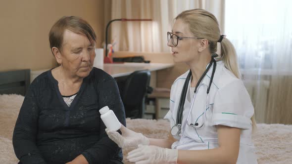  Medical consultation grandma at home. Explaining medicine pills drug to old elder patient alt