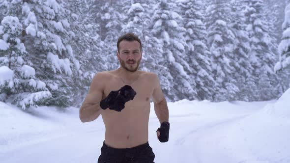Man with athletic body is running in the forest. alt