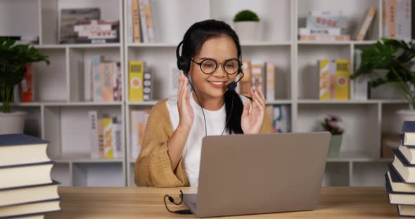 female student in headphones and glasses sit at desk alt