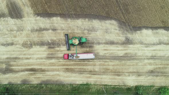 An Aerial View of a Harvester Dumping Grain Into a Truck Van After Harvesting