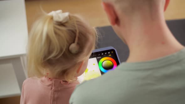A Child with Cochlear Implants Plays with a Tablet Computer with His Father alt
