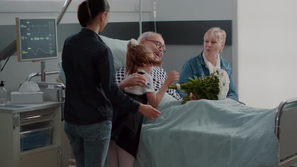 Family Visiting Elder Patient with Illness in Hospital Ward Bed alt