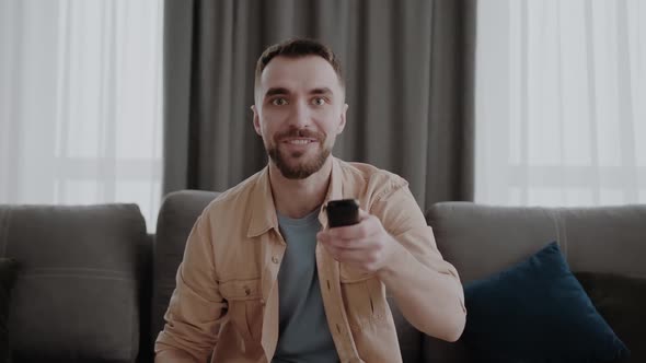 Remote Controller in Male Hands Happy Young Man Switching Channels on Smart Tv Choosing Film for alt