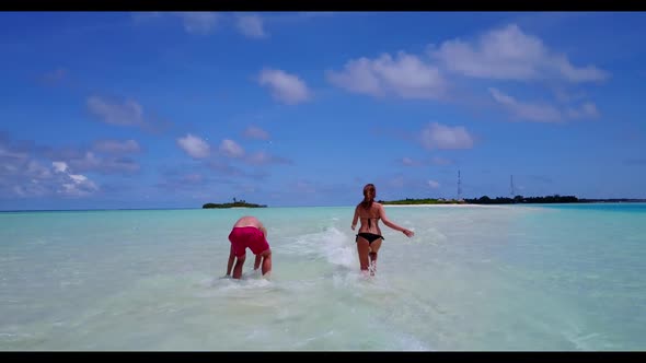 Man and lady posing on marine shore beach break by blue green water and clean sand background of the alt