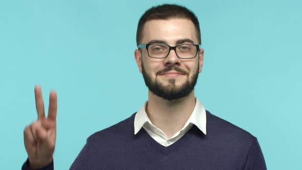 Slow Motion of Handsome Man Employee in Glasses Showing Peace Sign and Smiling Looking Hopeful at
