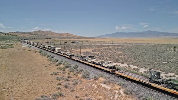 Train moving through the Utah desert loaded with military vehicles alt