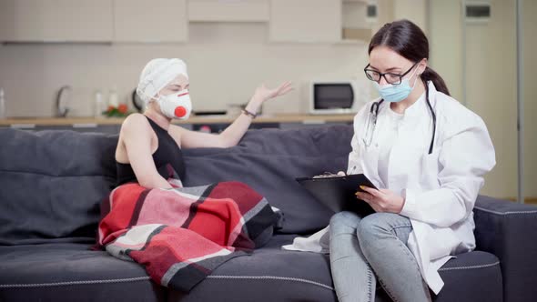 Concentrated Female Doctor in Eyeglasses and Covid Face Mask Taking Medical History of Patient  alt