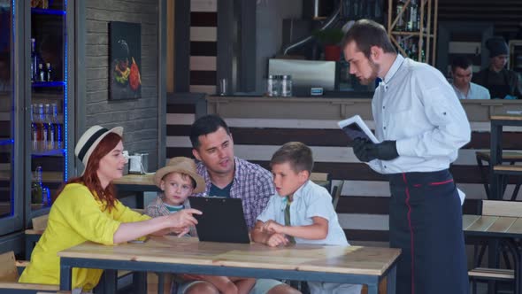 Lifestyle, Charming Married Couple with Young Male Children Enjoying a Family Vacation and Ordering alt