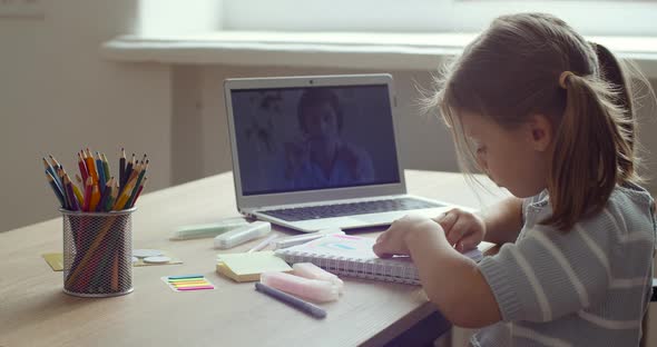 Side View of Teenager Preschool Girl Busy in Writing or Learning Drawing By Looking To Laptop Screen alt