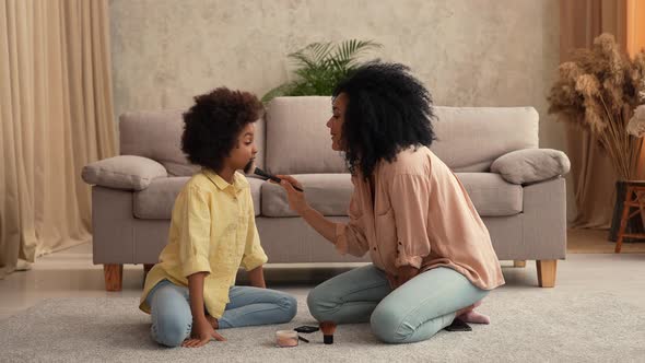 African American Woman Playing with Little Girl Using Makeup Brushes alt