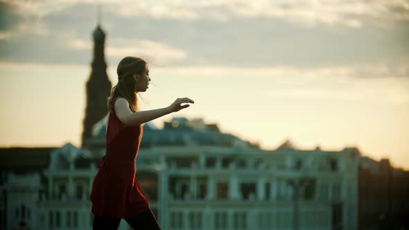 Young Woman Ballerina in Red Dress Dancing on the Roof alt