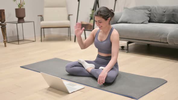 Indian Woman Talking on Video Call on Laptop on Yoga Mat alt