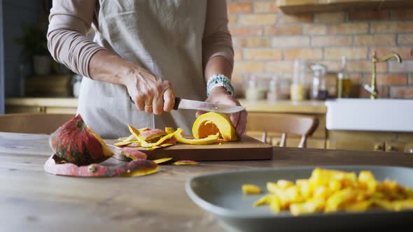 Aged Woman in White Pullover Hands Cut Yellow Pumpkin