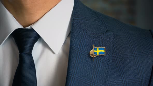 Businessman Walking Towards Camera With Country Flag Pin Sweden alt