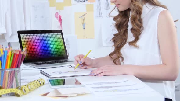 Fashion Designer Draws Sketches for a New Collection and Looks at the Computer alt