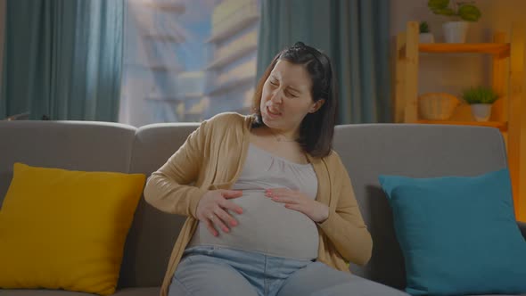 Pregnant Woman Sitting on the Couch Having Labor Contractions Pain alt