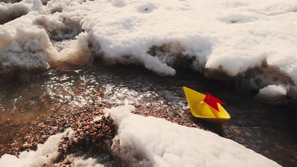 Winter Little Boat of Their Yellow Paper with a Red Flag is Floating on Stream
