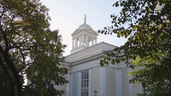 Historic view of Vanha Kirkko framed by trees on a blue sky day. alt