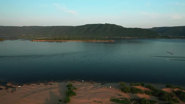 Helicopter View, River Coast, Sandy Beach with Tents, Tourism. Green Hills on the Other Side of the