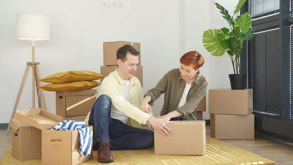 Man And Woman Help Each Other To Pack Stuffs And Use Scotch Tape A Box Before Moving To New House