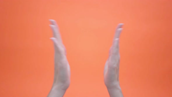 Woman Claps Her Hands on Isolated Orange Background and Then Gives Thumbs Up and Puts Her Hands in