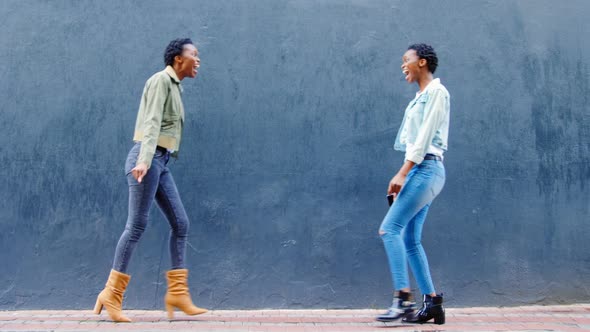 Twin sisters embracing each other on a sidewalk in the city 4k alt