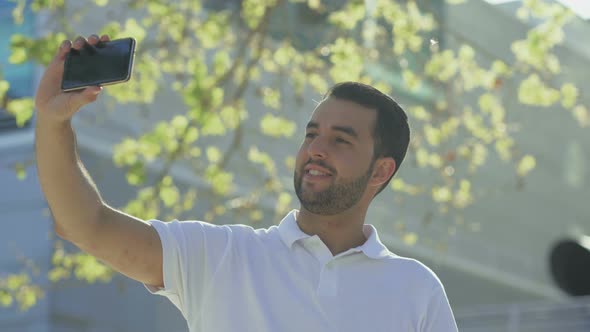 Smiling Bearded Man Taking Selfie with Smartphone alt